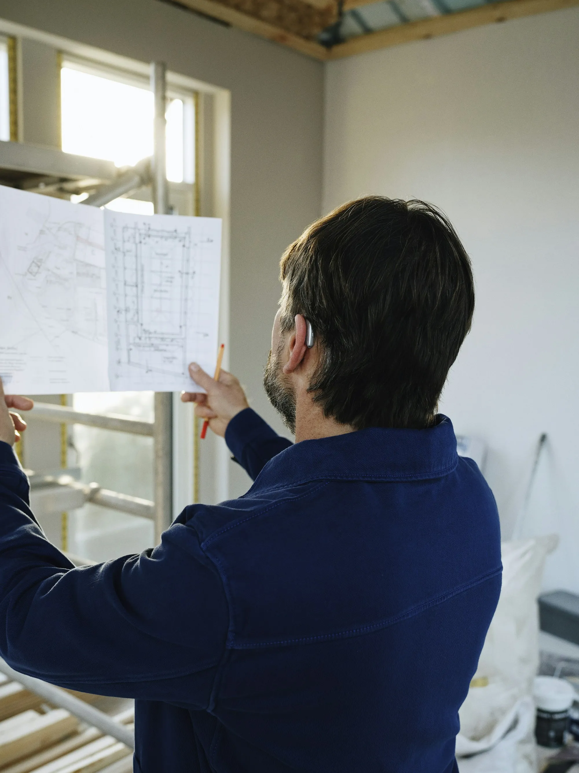 Contractor checking printed floor plans in a room under renovation