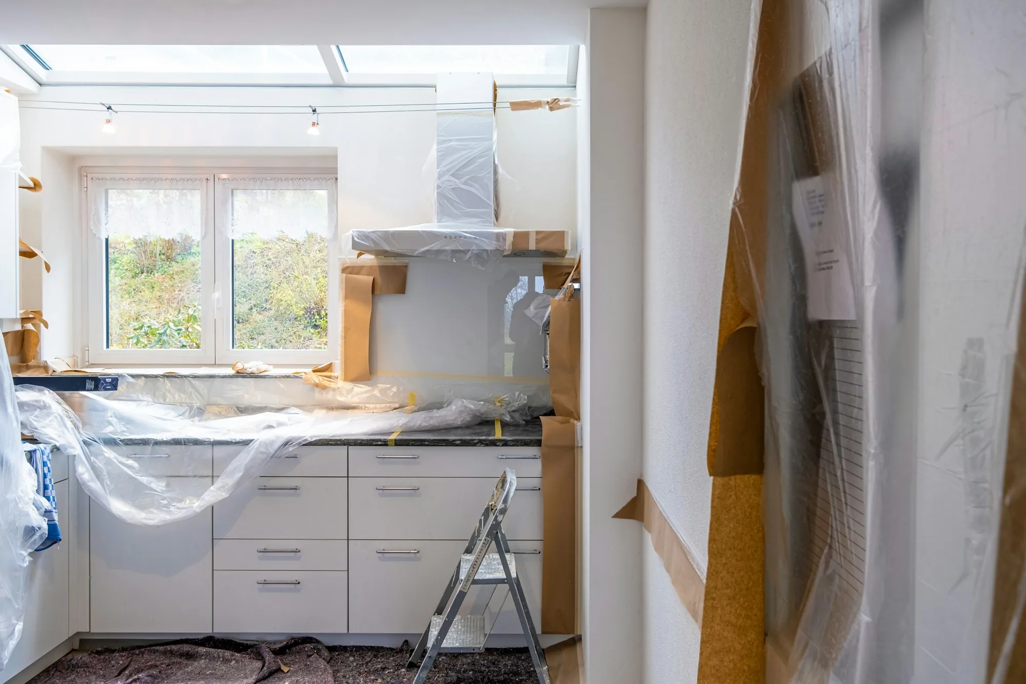 Kitchen cabinets, counters and range hood wrapped in plastic sheeting and paper during a remodel