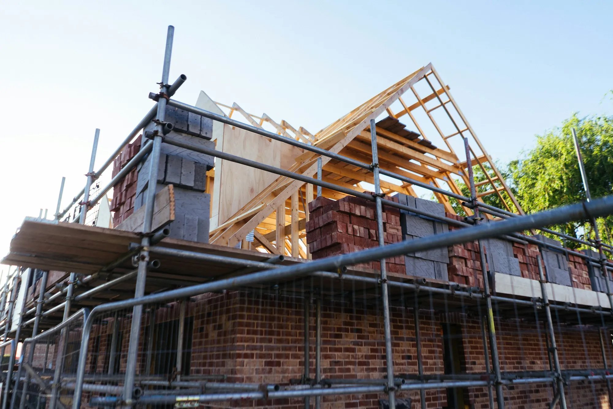 Brick house with a new upper-story addition framed in behind scaffolding